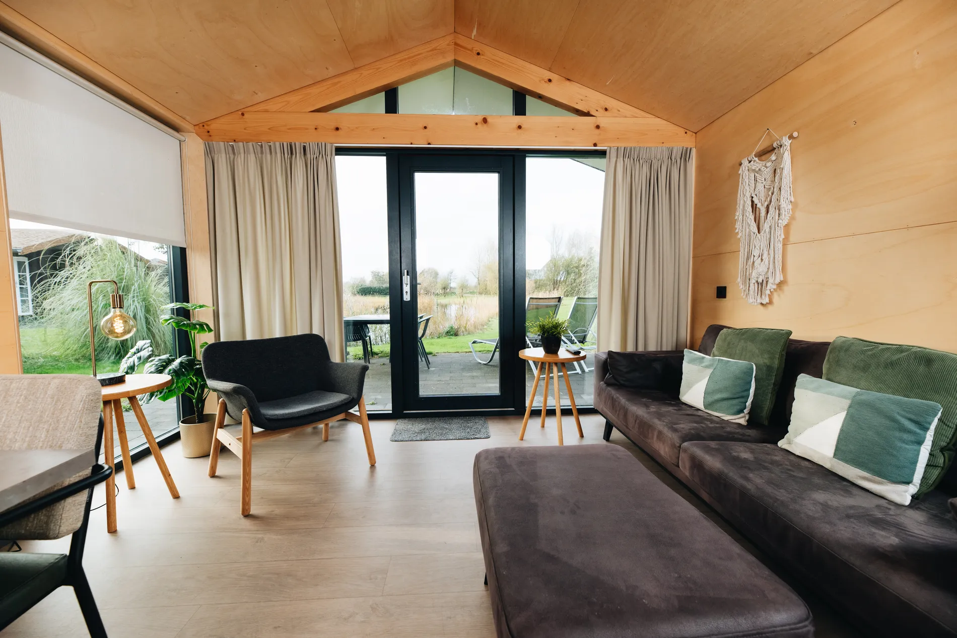 Lichte zithoek en terras van de Ecolodge bij Resort Land & Zee met uitzicht op het water.